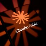 The Claude Fable logo is displayed on the screen of a smartphone placed on a reflective surface onto which the company's icon is projected.