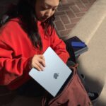 young woman putting Apple MacBook Air into a satchel