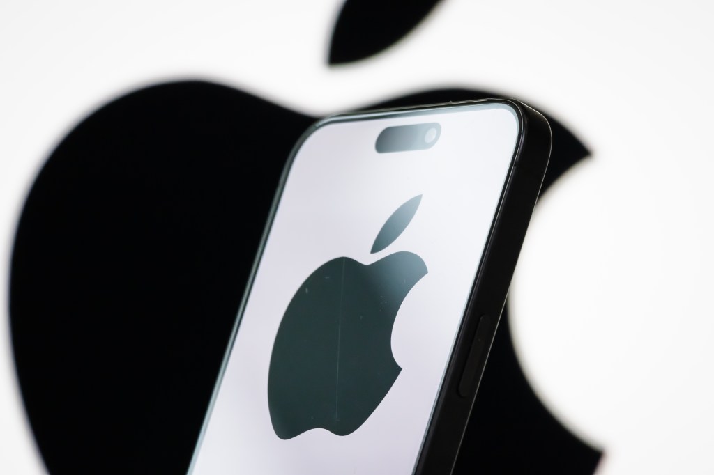 In this photo illustration, the logo of Apple Inc. is displayed on a smartphone screen, with the company's iconic black apple symbol visible in the background.
