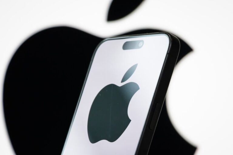 In this photo illustration, the logo of Apple Inc. is displayed on a smartphone screen, with the company's iconic black apple symbol visible in the background.