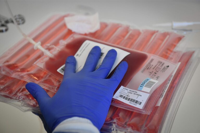 A lab tech preparing to thaw a frozen blood bag containing immune cells that will be modified into CAR T cells.