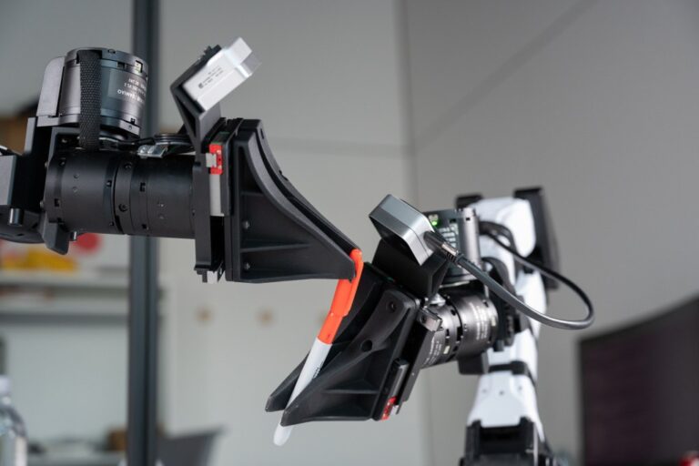 XDOF's robotic arms manipulate a pen and cap.