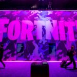 Attendees walk past signage for Epic Games Inc.'s Fortnite