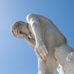 Man facepalming statue under the sun in the Tuileries garden.