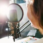 woman speaking into a microphone in a recording studio