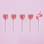 Five lollipop hearts on a pink floor, but the last one is smashed to pieces.