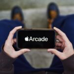 Apple Arcade video game subscription service signage is displayed on an iPhone