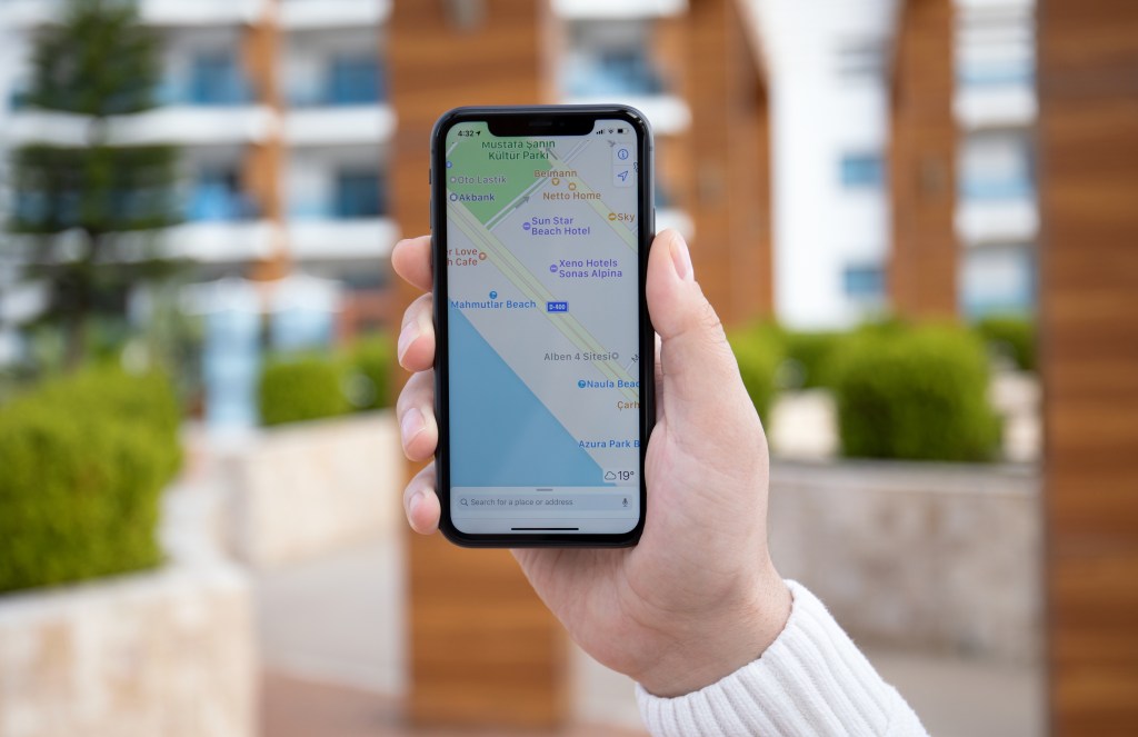 Man hand holding iPhone 11 with Apple Maps on screen