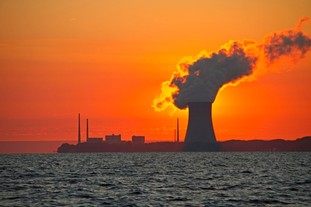 The sun rises behind a nuclear power plant cooling tower.