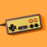 Retro video game controller on orange background.