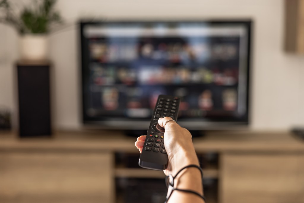 hand holding remote pointed at TV