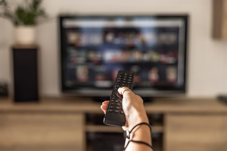 hand holding remote pointed at TV
