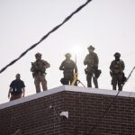 U.S. Immigration and Customs Enforcement (ICE) agents, Department of Homeland Security (DHS) personnel, and Border Patrol Commander Gregory Bovino stand together amidst a tense protest outside the ICE processing facility in Broadview, Illinois, on September 27, 2025.