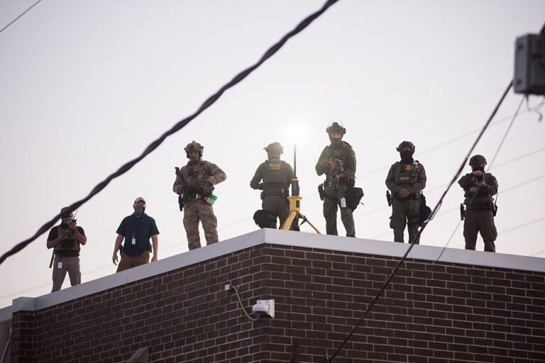 U.S. Immigration and Customs Enforcement (ICE) agents, Department of Homeland Security (DHS) personnel, and Border Patrol Commander Gregory Bovino stand together amidst a tense protest outside the ICE processing facility in Broadview, Illinois, on September 27, 2025.