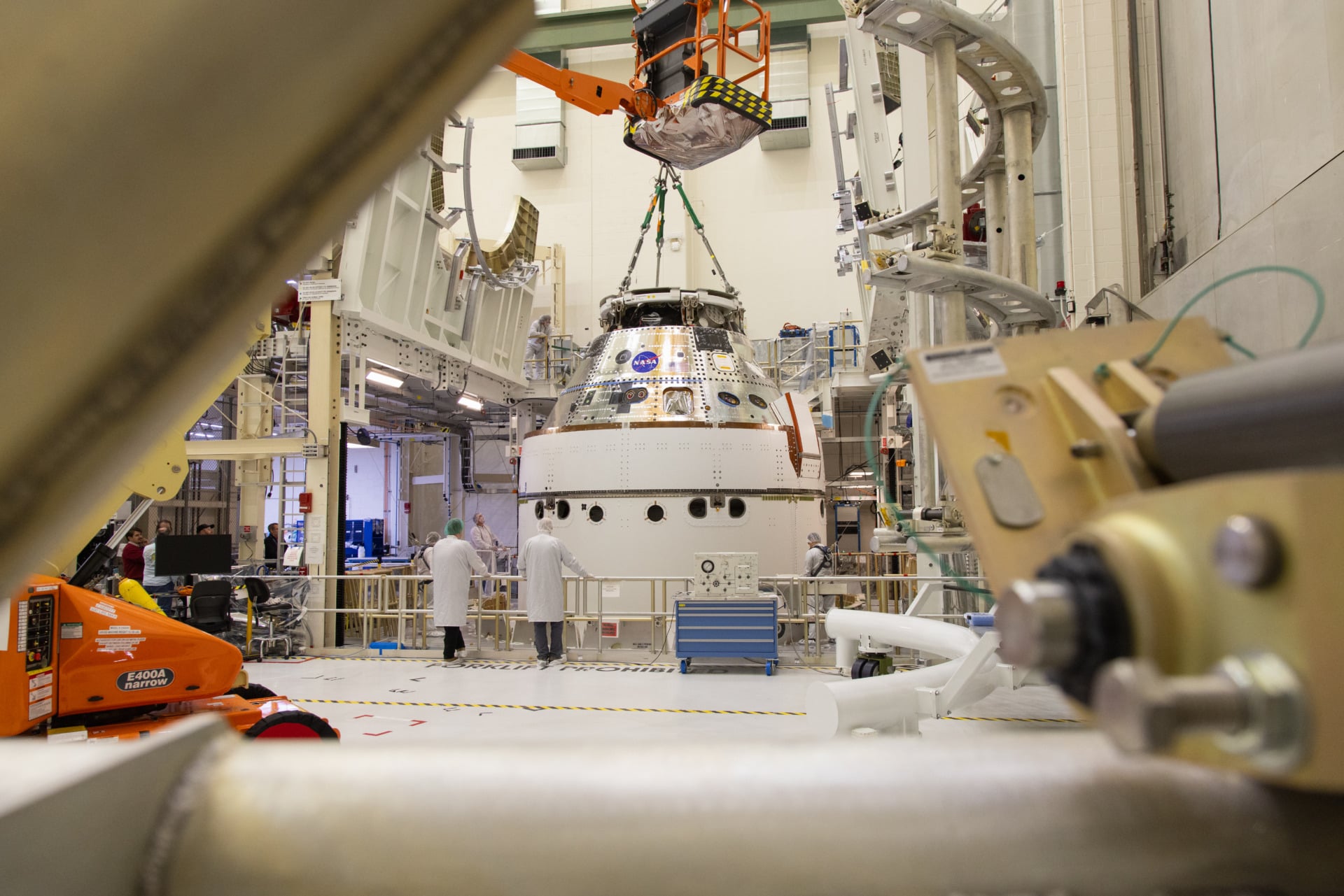 gsf-artemis-2-image-1 A crane returns NASA’s Artemis II Orion spacecraft to the Final Assembly and System Testing (FAST) cell inside the Neil A. Armstrong Operations and Checkout Building at NASA’s Kennedy Space Center in Florida on Friday, March 21, 2025, following installation of four solar array winds and adapter jettison fairings.