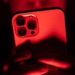 a person holding an iPhone facing the camera in a red backdrop