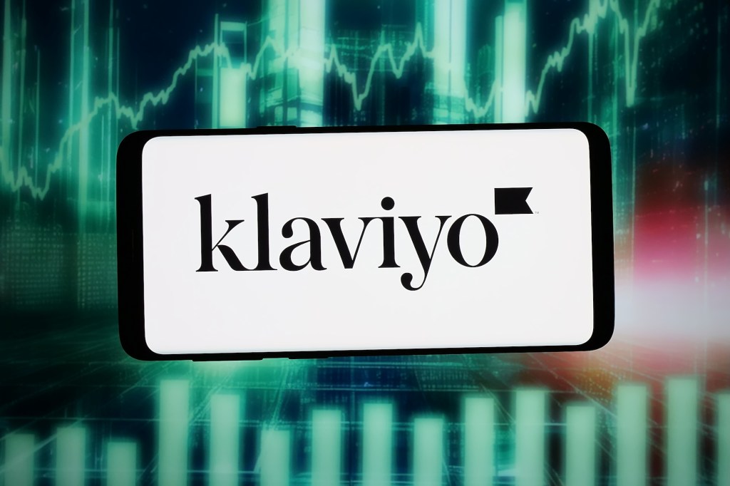 The logo of US marketing automation company Klaviyo Inc. is seen displayed on a smartphone in front of an abstract background on a computer screen.
