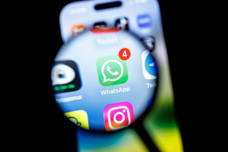 in this photo illustration, the Whatsapp app logo can be seen through a magnifying glass on the display of a smartphone.