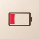 Paper Cut Craft Battery Only Has One Red Cell Left on Beige Background Directly Above View.