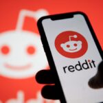 Reddit logo displayed on smartphone with Reddit logo in the background